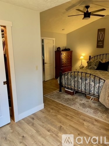 A bedroom with a bed, dresser, and ceiling fan.