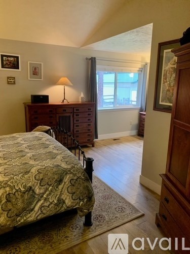 A bedroom with a bed, dresser, and window.