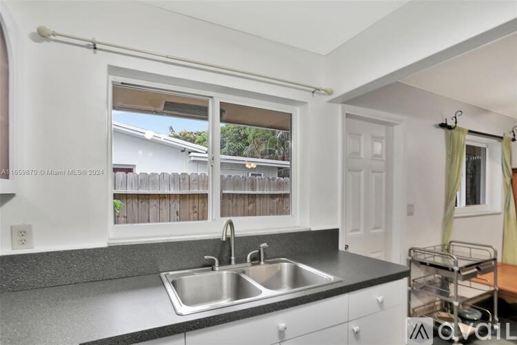 A kitchen with a sink and a window overlooking a fence.