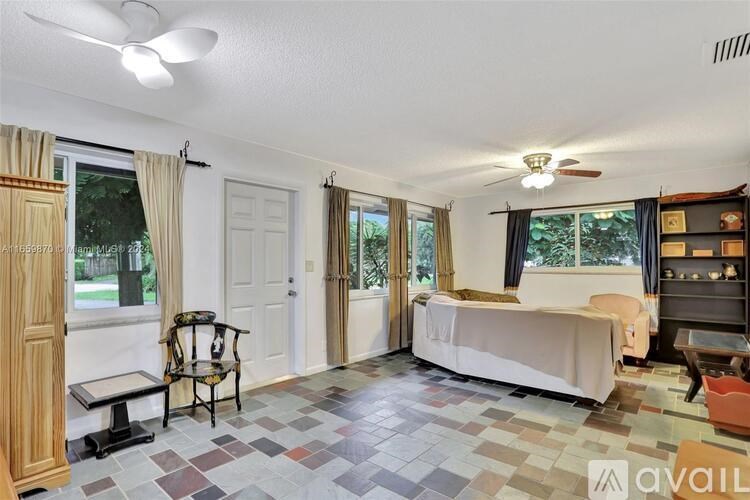 A bedroom with a bed, chair, and a fan.