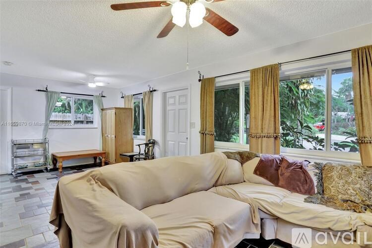 A living room with a beige couch and a ceiling fan.