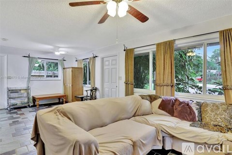 A living room with a beige couch and a ceiling fan.