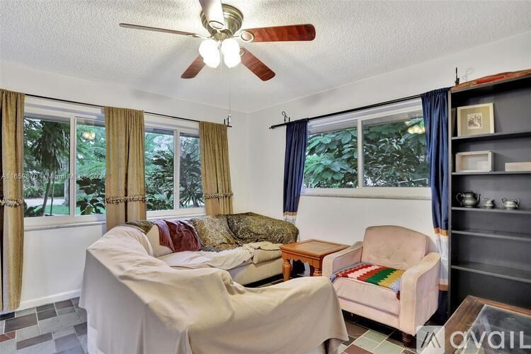 A living room with a fan, a couch, a chair, and a table.