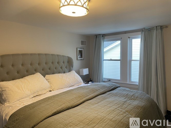 A bedroom with a large bed and a window with curtains.