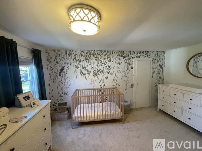 A baby's room with a crib, dresser, and wallpaper.