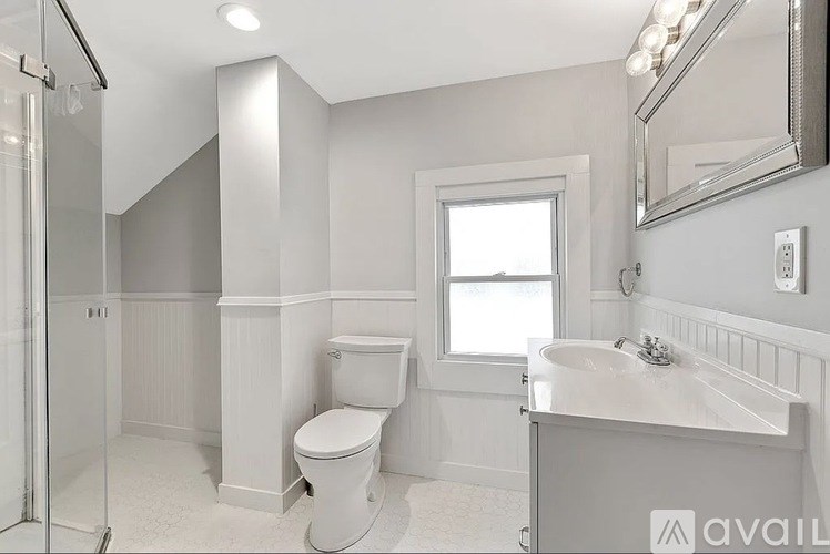 A bathroom with a toilet, sink, and mirror.