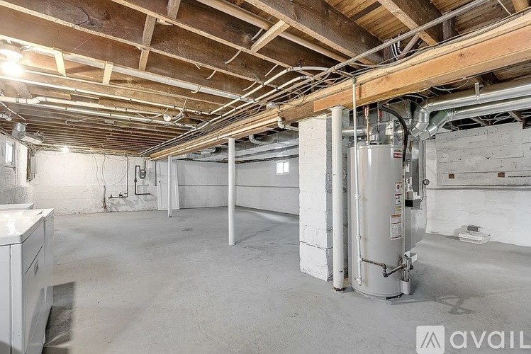 A large, empty room with a high ceiling and exposed pipes.