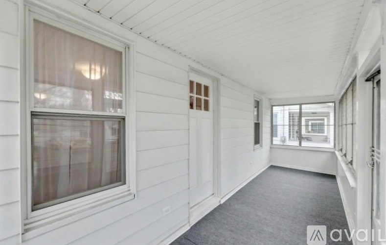 A long white hallway with a window and a door.