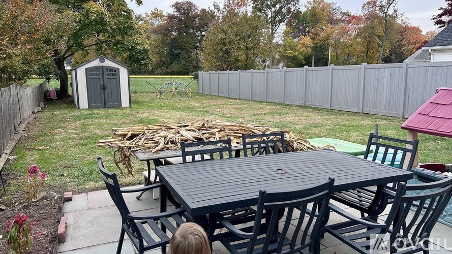 A backyard with a table and chairs and a shed.