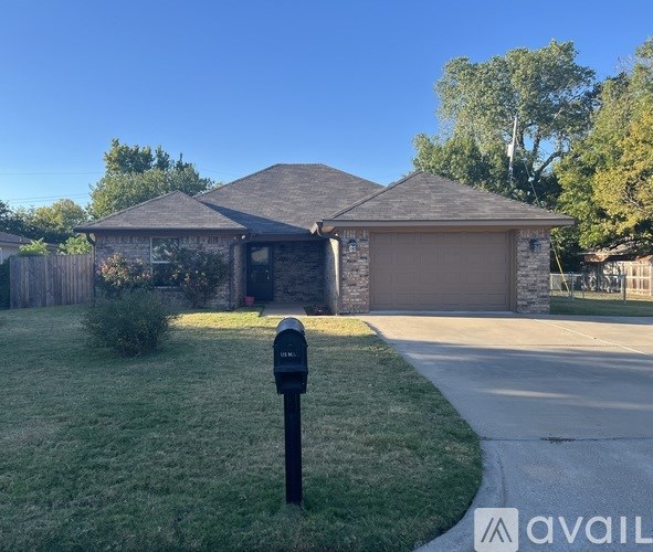 A house with a brown garage door and a black mailbox on a green lawn.