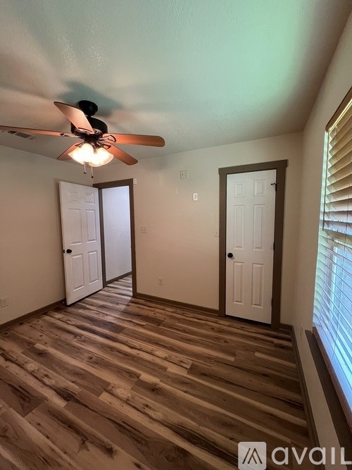 A room with a ceiling fan and wooden flooring.