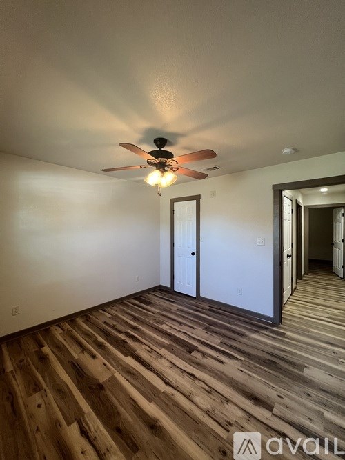 A room with wooden flooring and a ceiling fan.