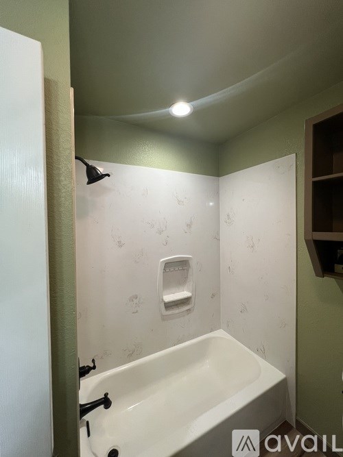 A bathroom with a white bathtub and a shower head.
