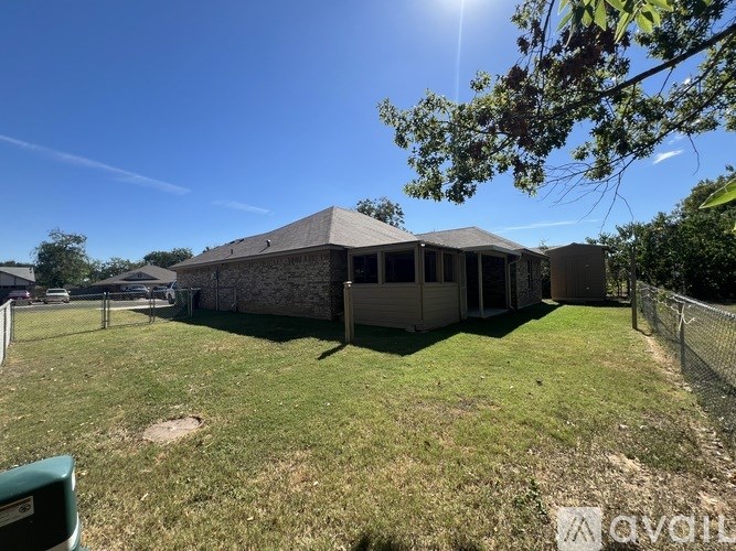 A house with a fence and a tree branch in the foreground.