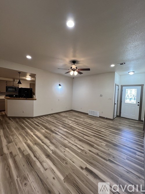 A spacious room with wooden flooring and a ceiling fan.
