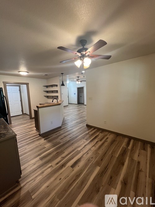 A room with a ceiling fan and wooden flooring.