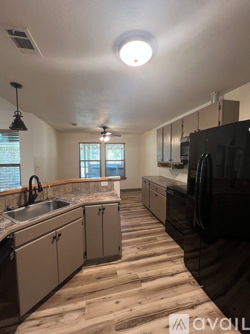 A kitchen with wooden floors and black appliances.