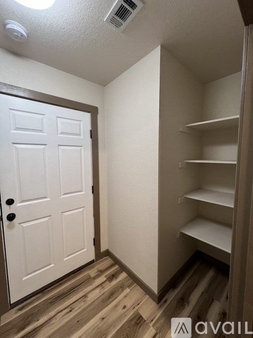 A white door is in a room with a shelving unit.