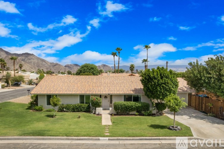 A house with a brown roof and a green lawn in front.