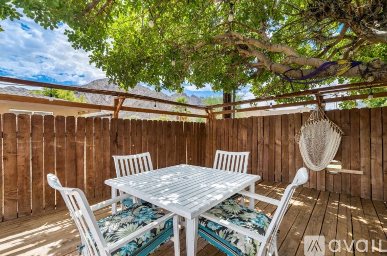 A white table and chairs are set up on a wooden deck.