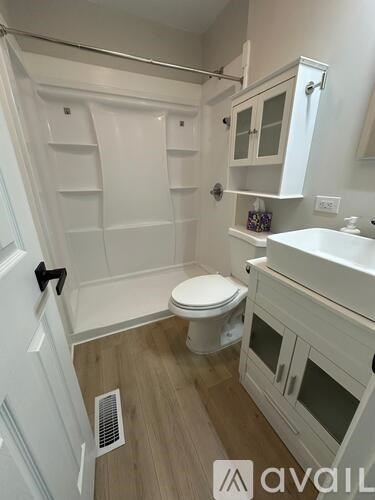 A white bathroom with a toilet, sink, and shower.