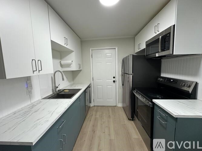 A kitchen with white cabinets and a black refrigerator.