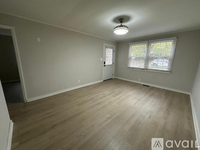 A room with wooden flooring and a window with blinds.