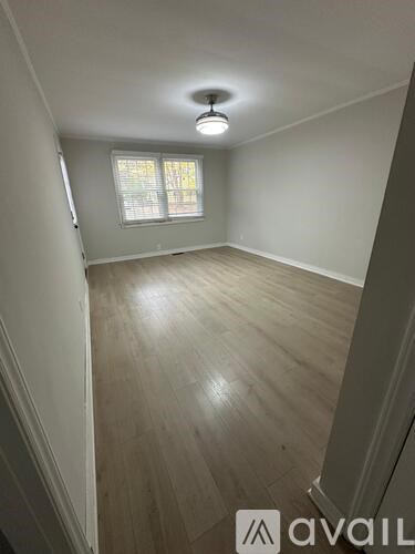 A room with wooden flooring and a window with blinds.