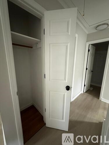 A white door is in a hallway with a wooden floor.