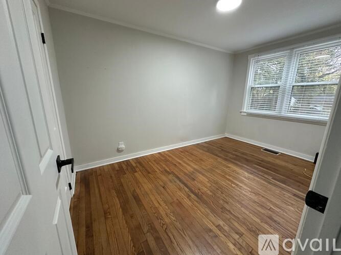 A room with wooden flooring and a window with blinds.