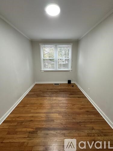 A room with wooden flooring and a window with blinds.