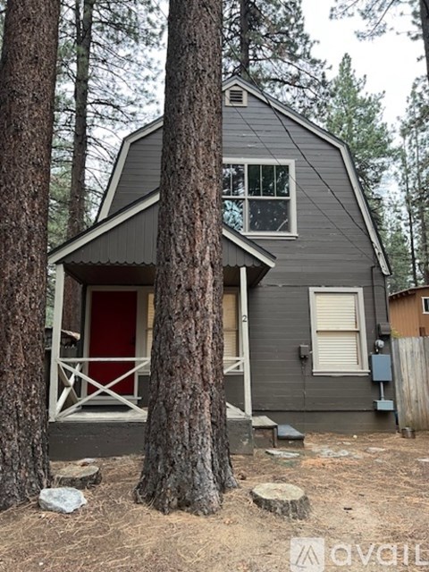 A house with a red door is surrounded by trees.