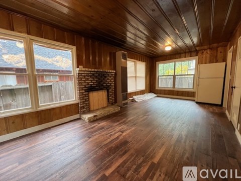 A room with wooden floors and a brick fireplace is available for rent.