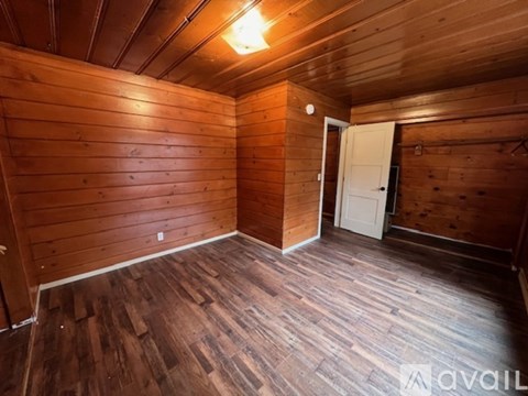 A room with wooden walls and floor and a door.