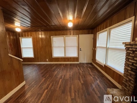 A room with wooden walls and floor and a brick fireplace.