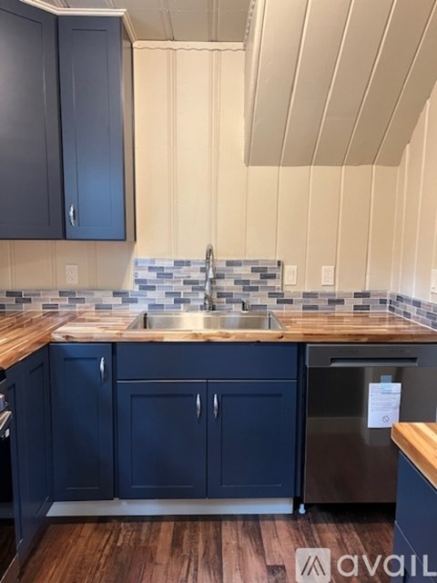 A kitchen with dark blue cabinets and a wooden counter top.