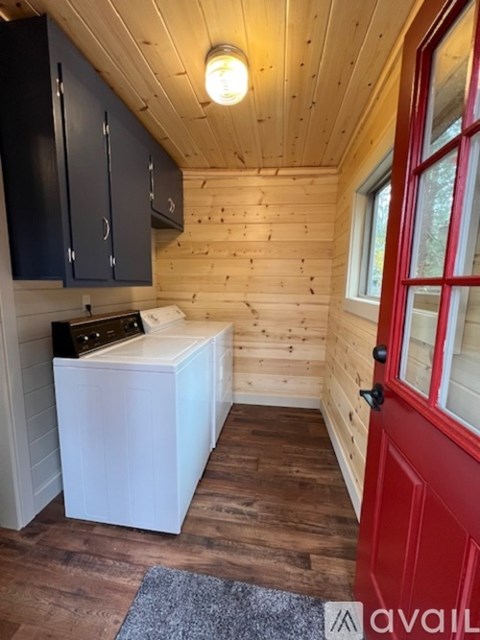 A small kitchen with a red door and a white dishwasher.
