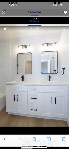A white bathroom vanity with two sinks and a mirror above each.