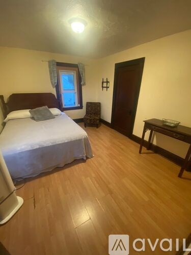 A bedroom with a bed, a chair, and a desk.