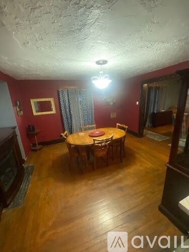 A room with a wooden floor and a round table with chairs.