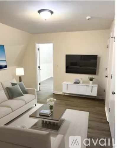 A living room with a white couch and a television on the wall.