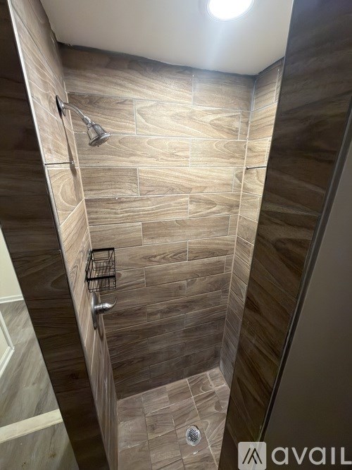 A bathroom with a tiled shower and a basket on the wall.