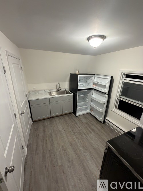 A kitchen with a refrigerator, sink, and cabinets.