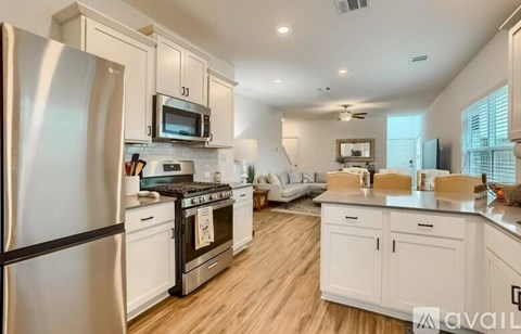 A kitchen with white cabinets and a black fridge.