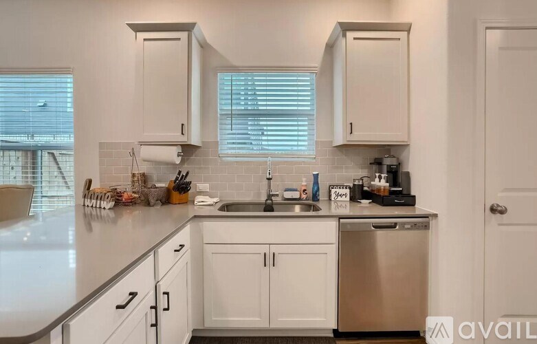 A kitchen with white cabinets and a stainless steel dishwasher.