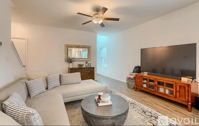 A living room with a grey couch, a coffee table, a flat screen TV, and a mirror.