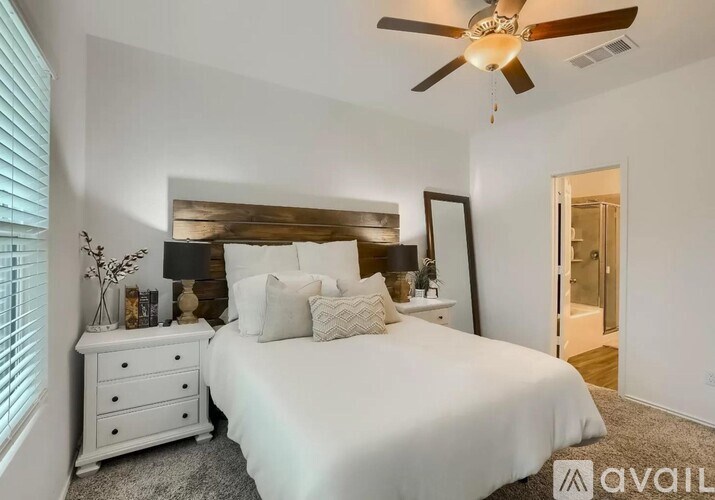 A bedroom with a white bed, a white dresser, and a ceiling fan.