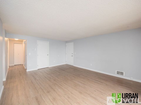 A spacious room with wooden flooring and white walls.