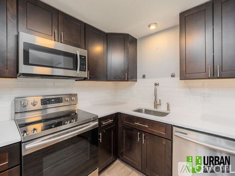 A modern kitchen with dark wood cabinets and stainless steel appliances.