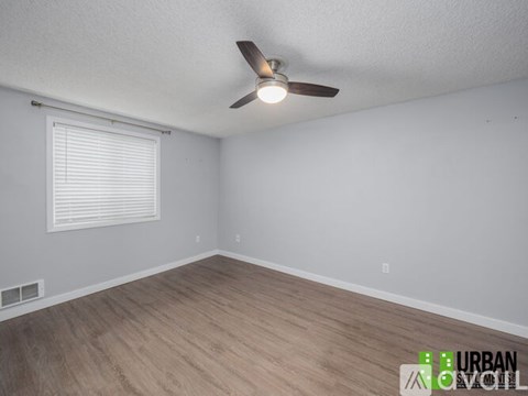 A room with a ceiling fan and wooden flooring.